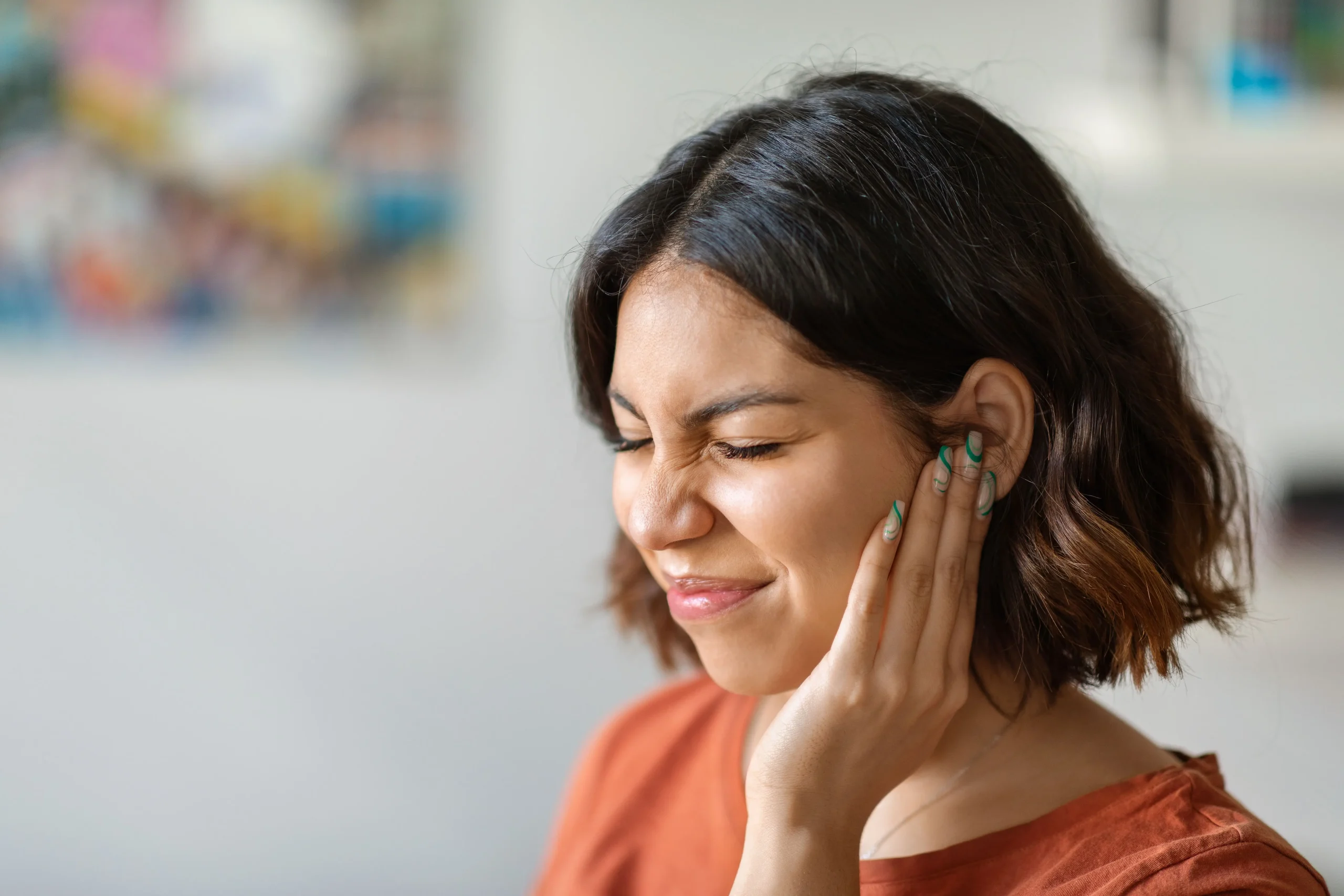 Frau hält sich das Ohr zu, sie hat tinnitus